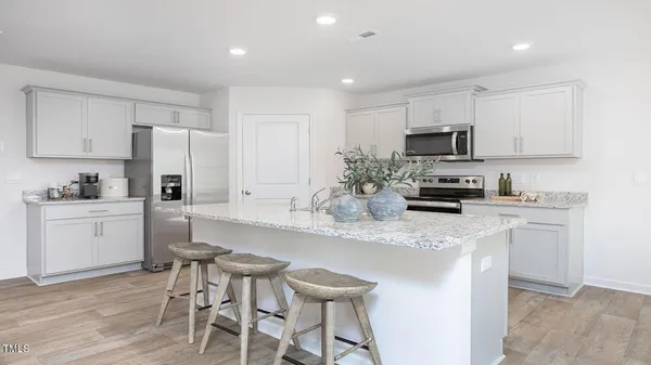 a kitchen with kitchen island granite countertop a sink cabinets and stainless steel appliances