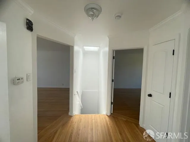 a view of a hallway with wooden floor and a bathroom