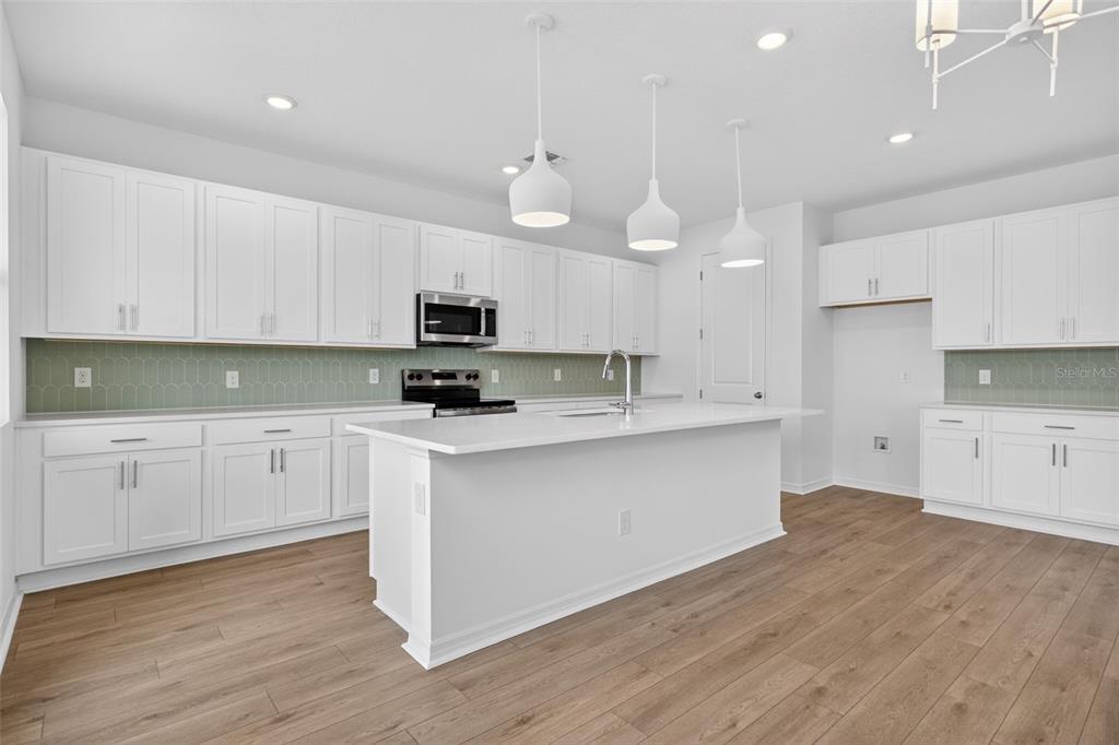 5765 Haystack Drive St. Cloud, FL 34771 - Photo 12 of 42 a large kitchen with cabinets wooden floor and stainless steel appliances