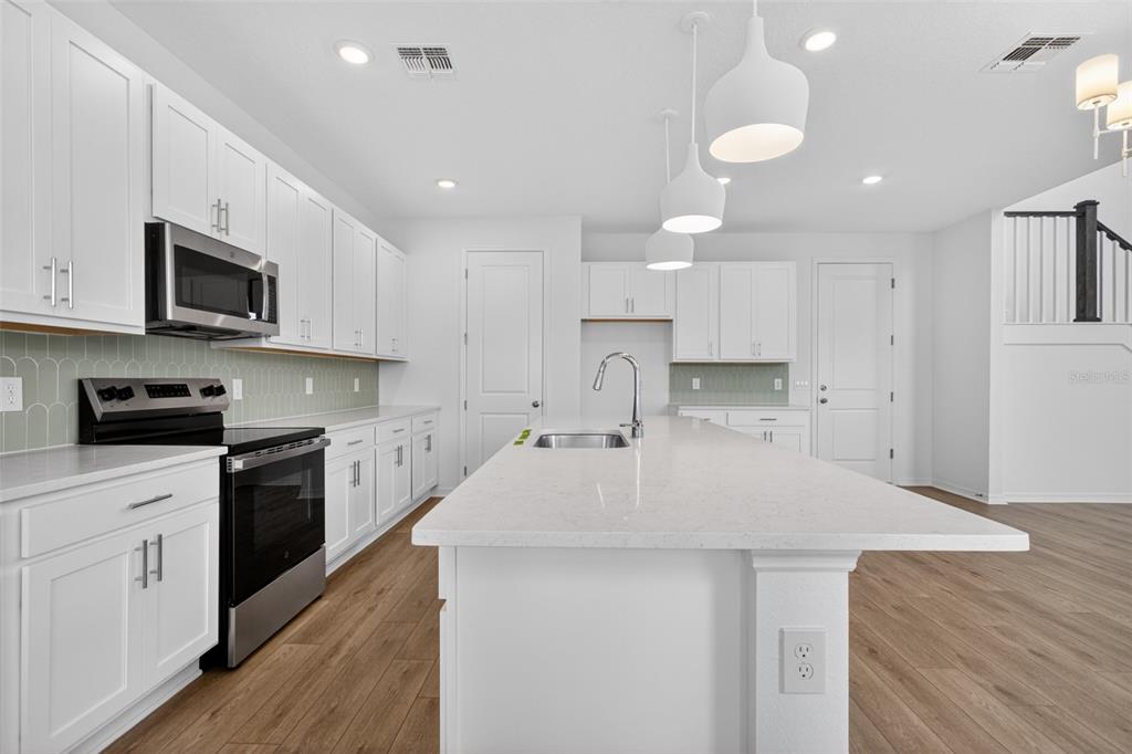5765 Haystack Drive St. Cloud, FL 34771 - Photo 14 of 42 a kitchen with a sink a stove top oven and white kitchen