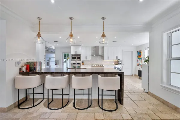 a kitchen with stainless steel appliances kitchen island granite countertop a table chairs and a refrigerator