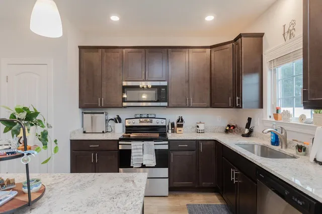 a kitchen with stainless steel appliances a sink a stove top oven a counter space and cabinets