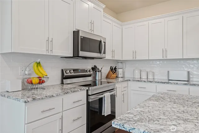 a kitchen with stainless steel appliances granite countertop a sink stove and microwave