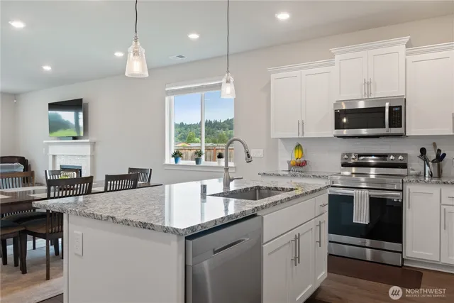 a kitchen with granite countertop a sink stove and microwave