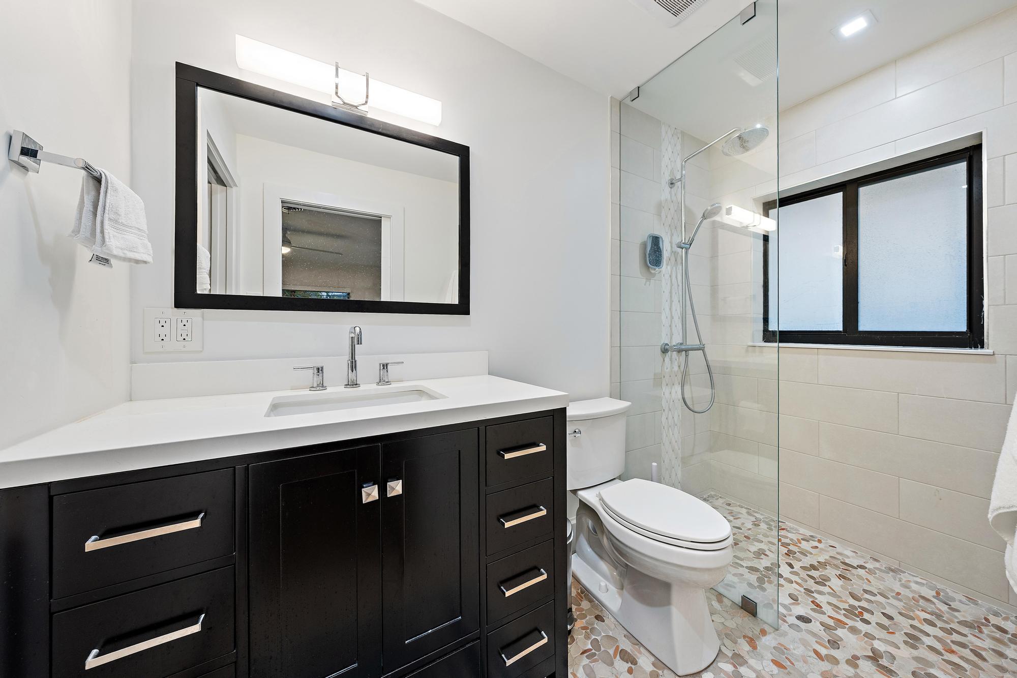 1120 Singer Drive Riviera Beach, FL 33404 - Photo 15 of 37 a bathroom with a toilet a sink a mirror a vanity and shower