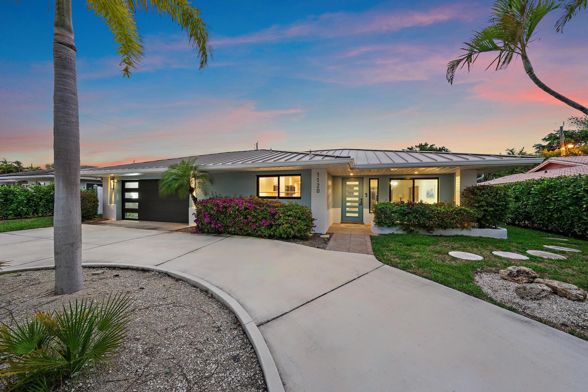 1120 Singer Drive Riviera Beach, FL 33404 - Photo 18 of 37 a front view of a house with a yard and potted plants