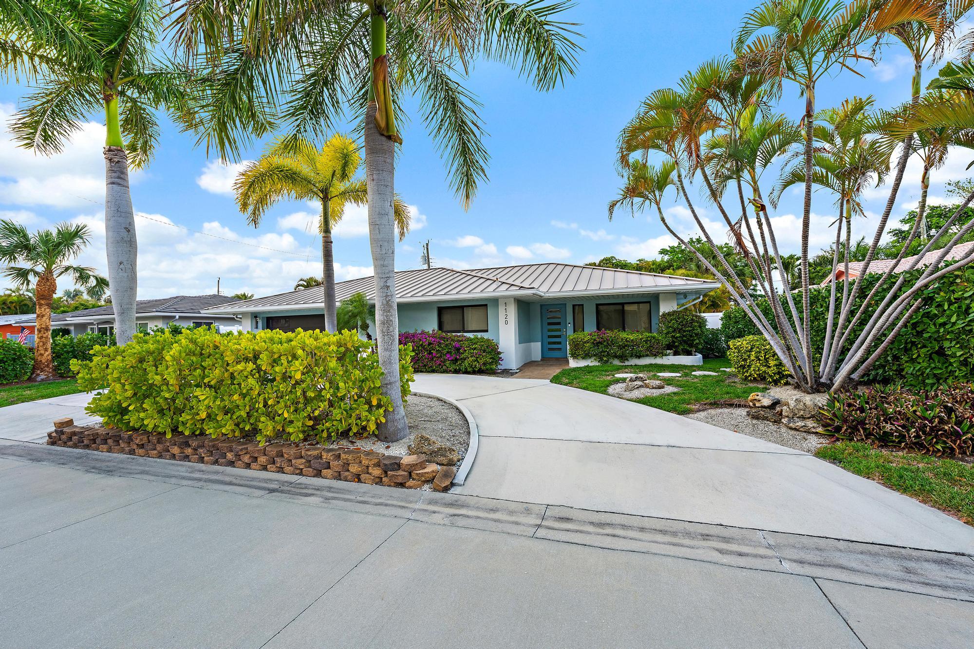1120 Singer Drive Riviera Beach, FL 33404 - Photo 23 of 37 a front view of a house with a garden and a yard