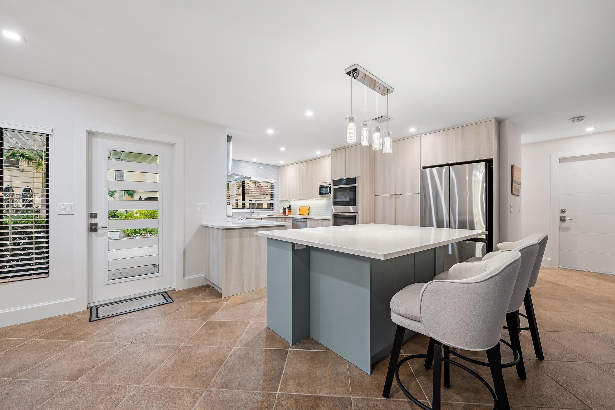 1120 Singer Drive Riviera Beach, FL 33404 - Photo 5 of 37 a kitchen with a table chairs refrigerator and cabinets