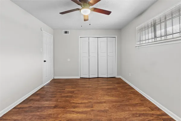 a view of an empty room with chandelier fan and wooden floor