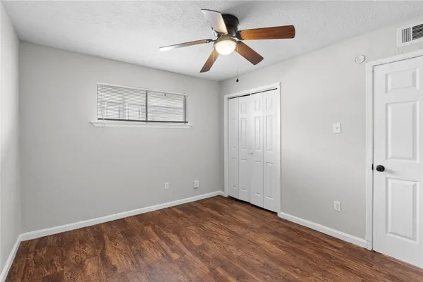 an empty room with wooden floor ceiling fan and windows
