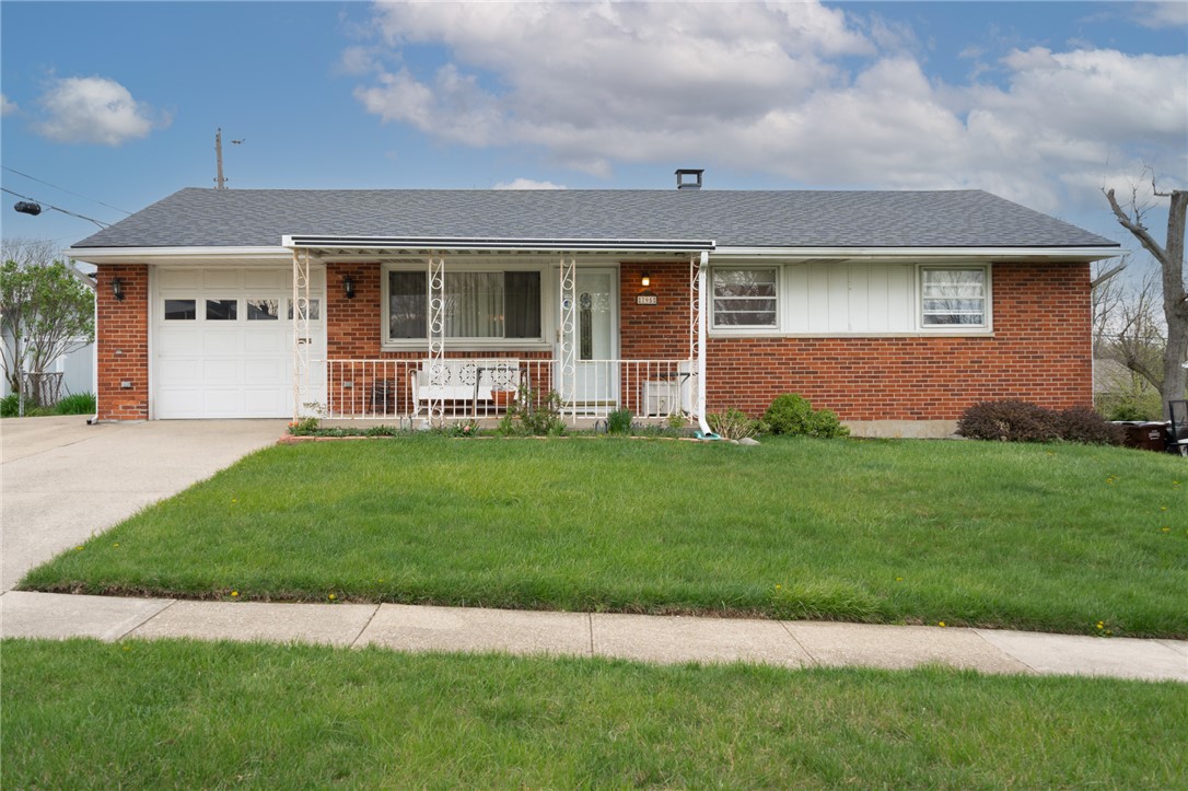 795 Spring Garden Place Dayton, OH 45431 - Photo 2 of 34 This classic brick residence offers a welcoming facade with a well-maintained lawn and an attached garage.