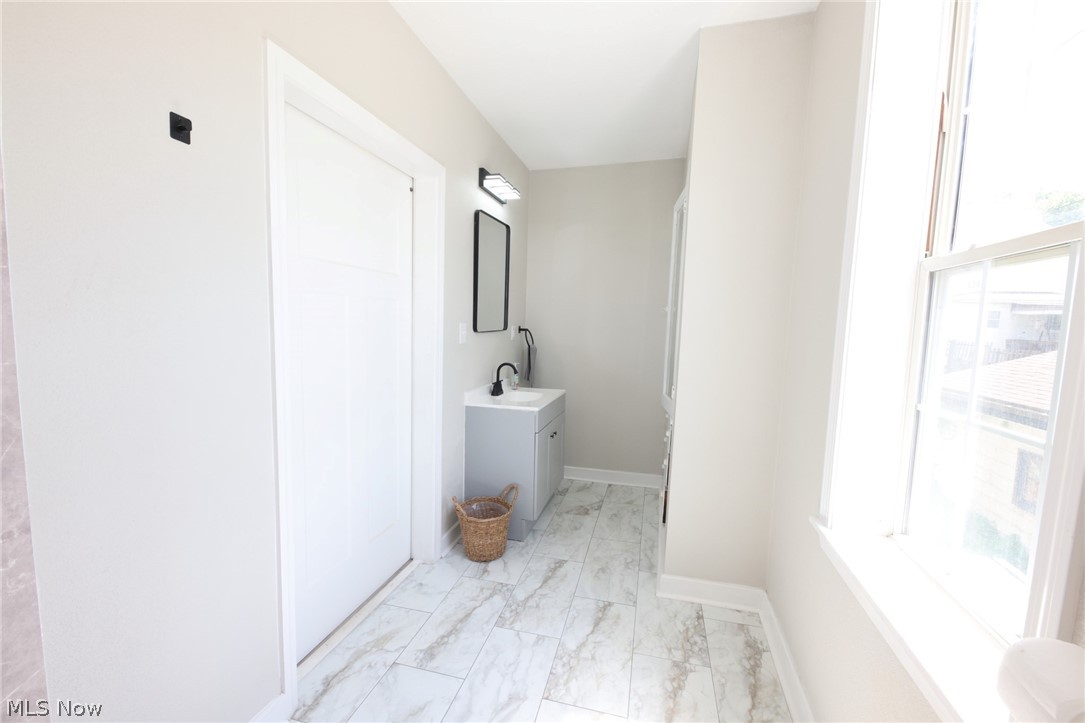416 5th Street Chester, WV 26034 - Photo 7 of 24 Light-filled interior featuring marble-look floor tile, a single-pane window, and a gray vanity with a vessel sink