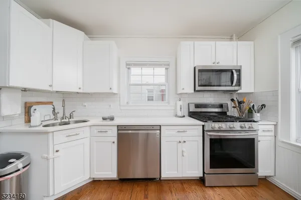a kitchen with cabinets stainless steel appliances a sink and wooden floor