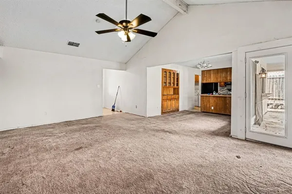 a view of a livingroom with a chandelier fan and kitchen view