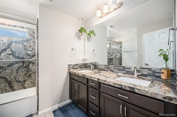 a bathroom with a granite countertop sink a mirror and a shower