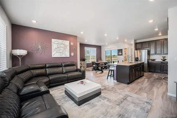 a living room with furniture wooden floor and kitchen view
