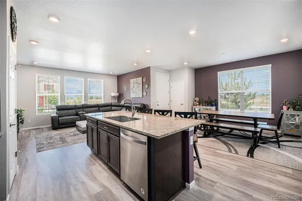 a kitchen with a stove a sink a kitchen island with chairs and wooden floor