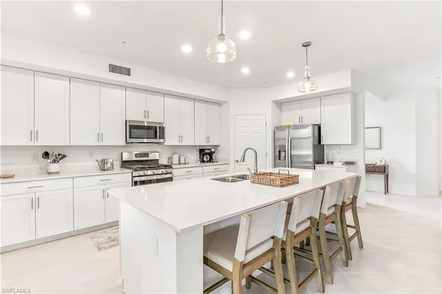 a kitchen with stainless steel appliances kitchen island granite countertop a dining table chairs and white cabinets