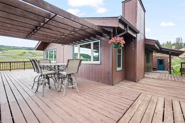 a view of a roof deck with table and chairs under an umbrella with wooden floor