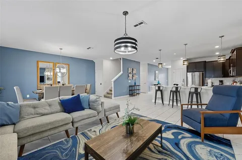 a living room with furniture kitchen view and a chandelier