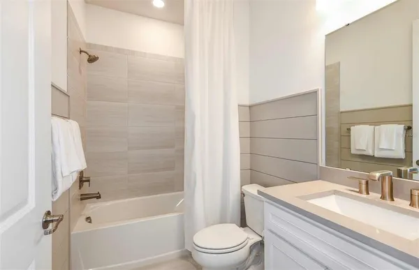 a bathroom with a granite countertop bathtub shower sink vanity mirror and toilet