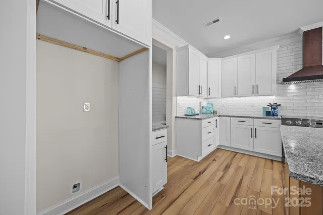a kitchen with white cabinets and wooden floor