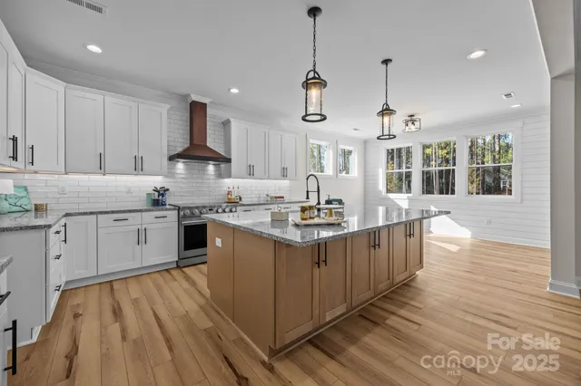 a kitchen with stainless steel appliances granite countertop a sink a stove and a wooden floors