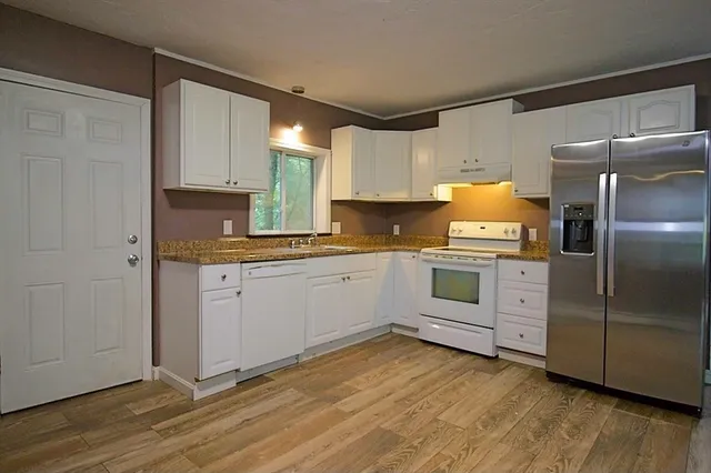 a kitchen with a refrigerator and white cabinets