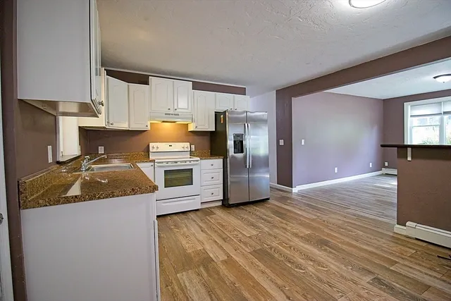 a kitchen with granite countertop a refrigerator and a stove top oven