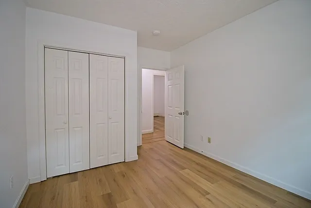 a view of an empty room with closet and a window