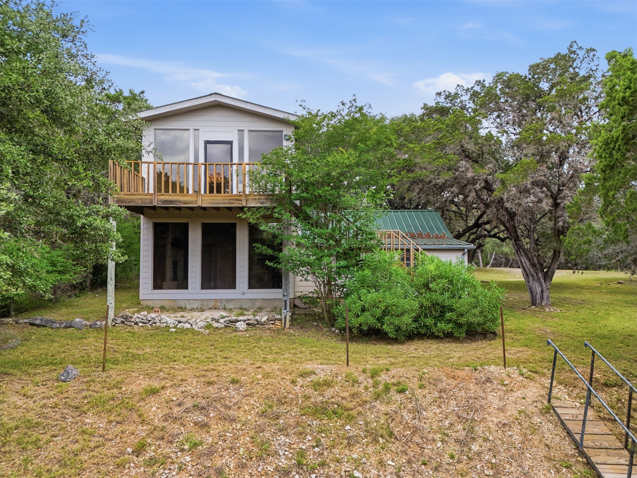 1260 Magers Road Concan, TX 78838 - Photo 23 of 40 A charming two-story home with an upper-level balcony and lower-level porch, nestled amidst mature trees.