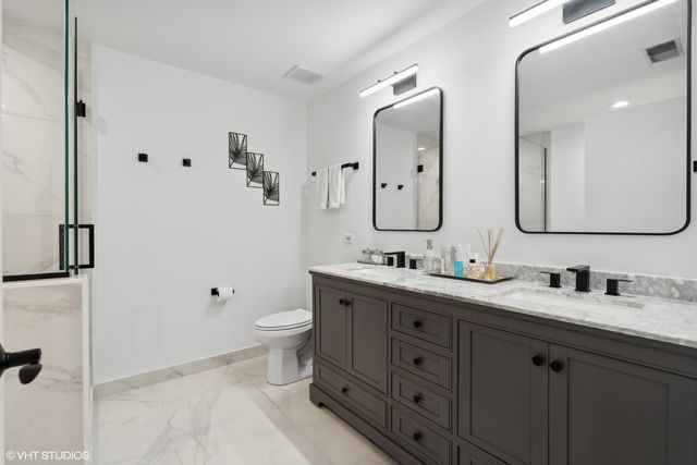 a bathroom with double vanity sink a mirror and a toilet