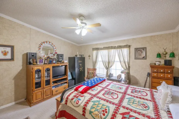 a bedroom with a bed a dresser and a chandelier