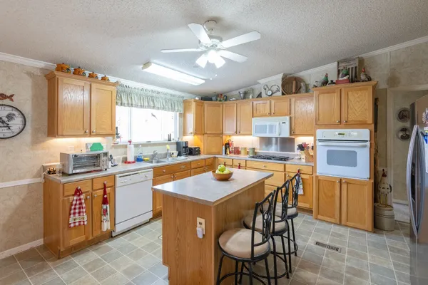 a kitchen with stainless steel appliances granite countertop a table chairs sink refrigerator and cabinets