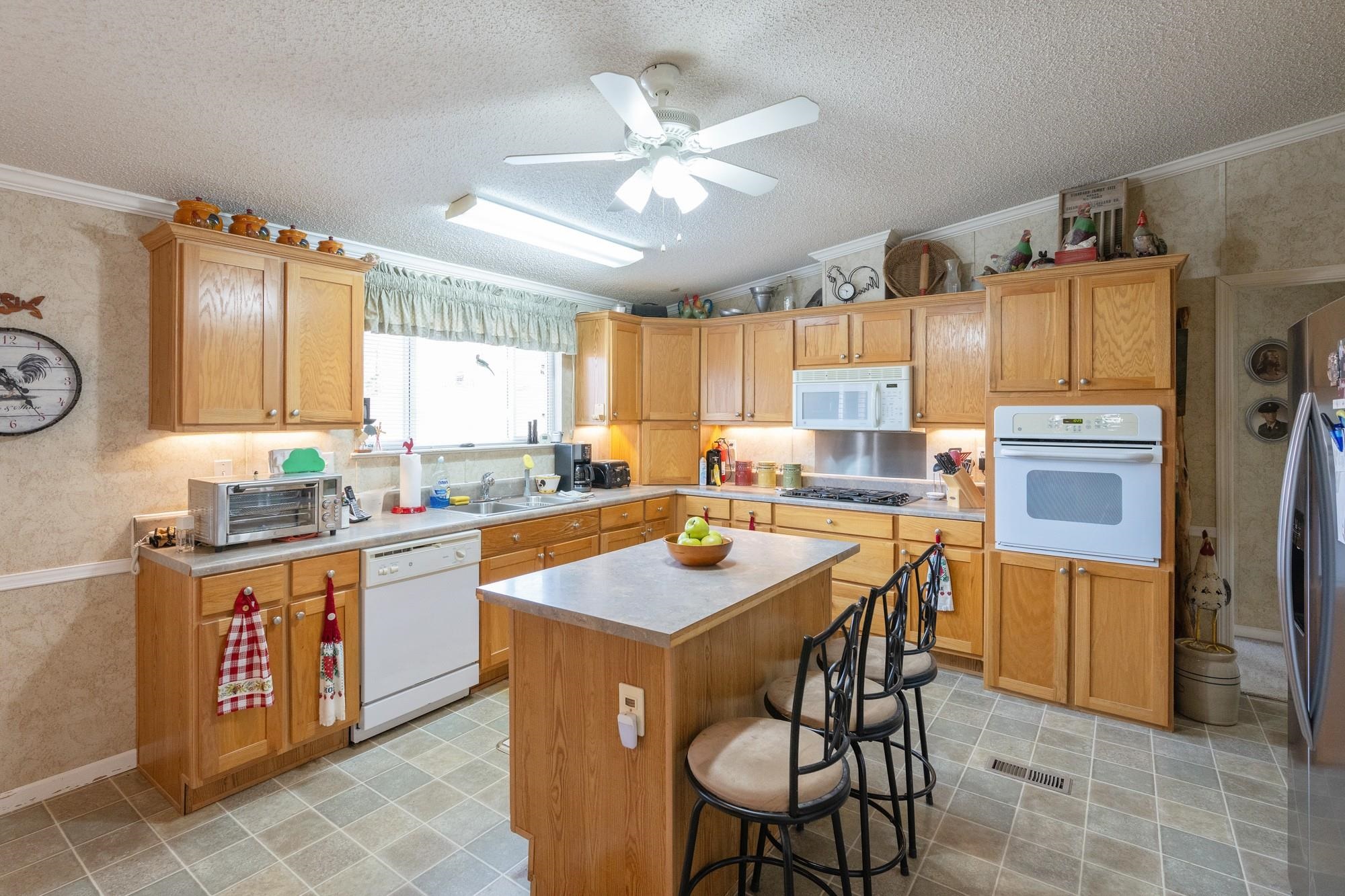 416 Haney School Road Decaturville, TN 38329 - Photo 5 of 35 a kitchen with stainless steel appliances granite countertop a table chairs sink refrigerator and cabinets