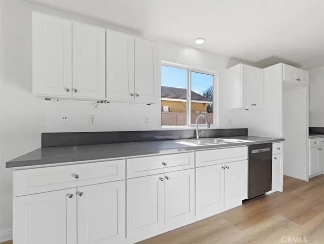 a kitchen with granite countertop a sink and cabinets with wooden floor