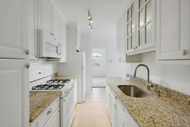 a kitchen with granite countertop a sink stove top oven and cabinets