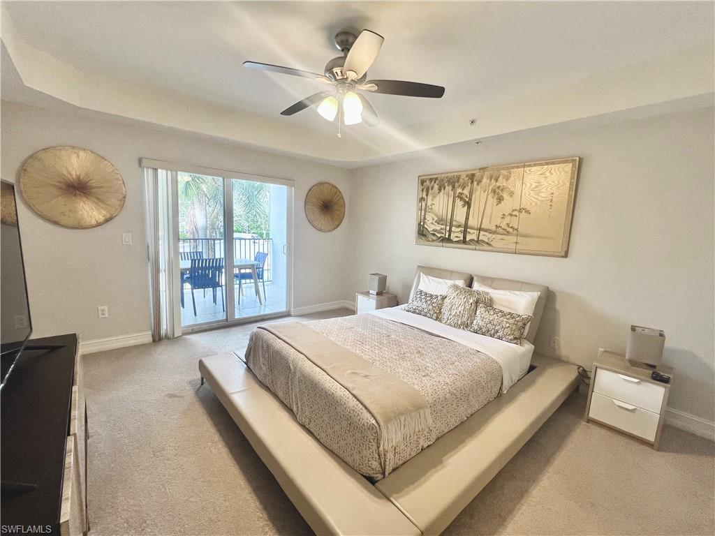 Carpeted bedroom featuring a tray ceiling, access to exterior, ceiling fan, and baseboards