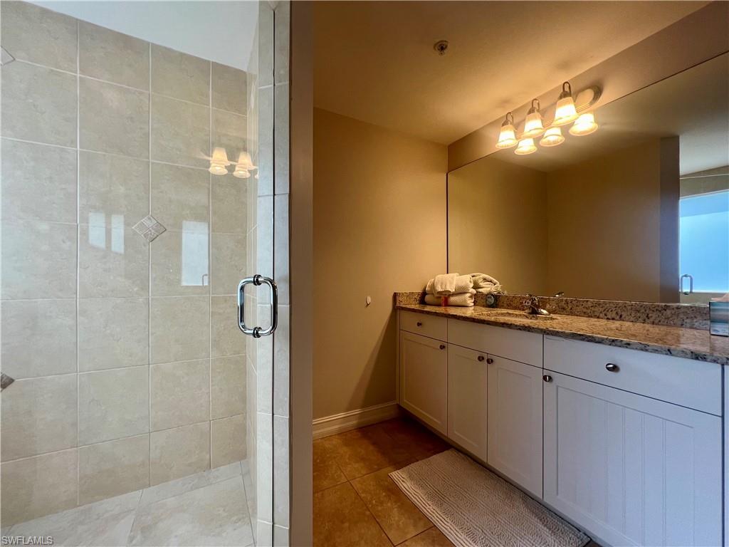 Full bathroom featuring tile patterned floors, vanity, baseboards, and a stall shower