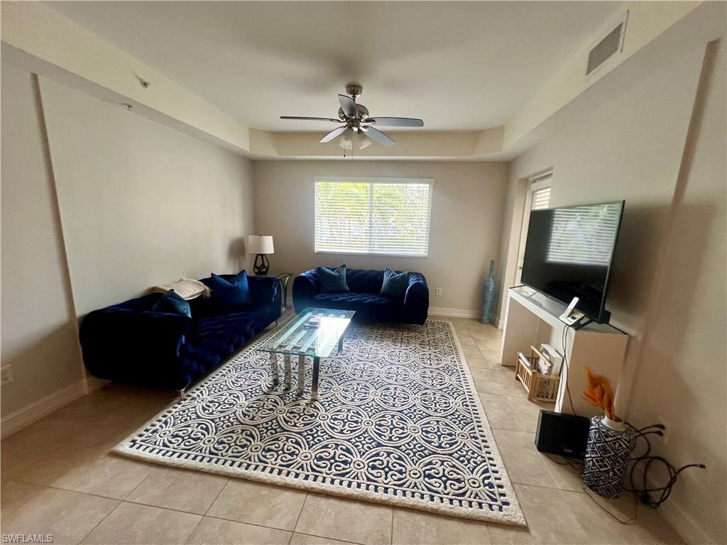 Living area featuring light tile patterned floors, baseboards, a ceiling fan, and visible vents