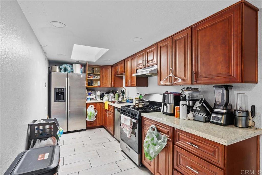 735 Osage Street Spring Valley, CA 91977 - Photo 12 of 25 a kitchen with stainless steel appliances granite countertop a stove a sink dishwasher and a refrigerator with wooden cabinets