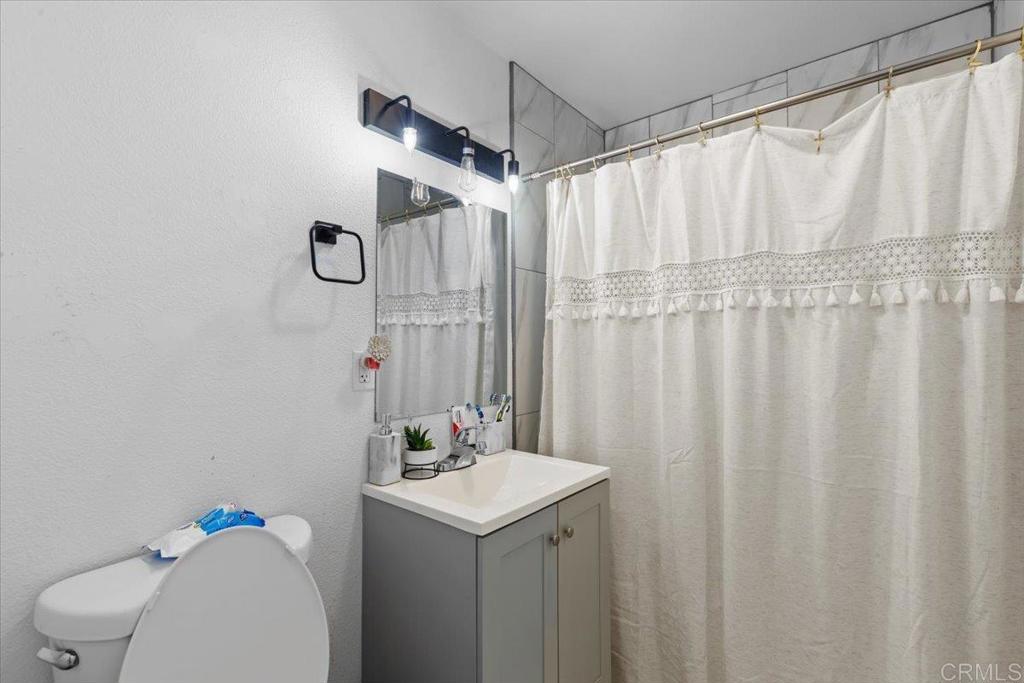 735 Osage Street Spring Valley, CA 91977 - Photo 18 of 25 a bathroom with a sink a toilet and shower curtain