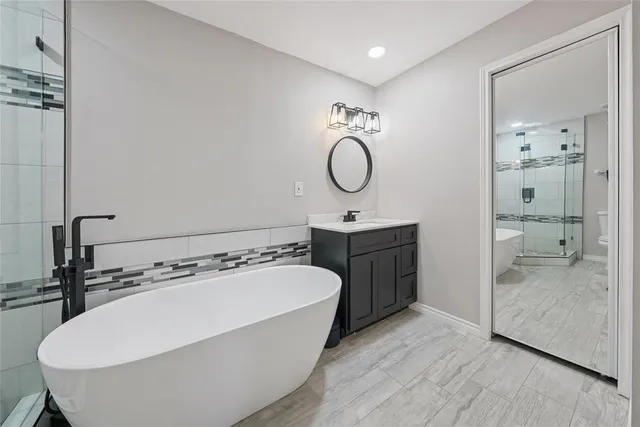 a bathroom with a tub sink shower and mirror