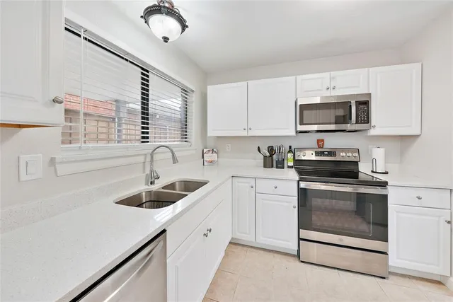 a kitchen with granite countertop white cabinets white stainless steel appliances and a sink