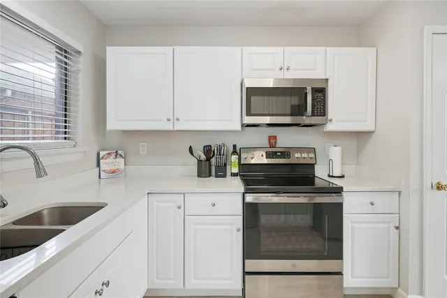 a kitchen with white cabinets and stainless steel appliances