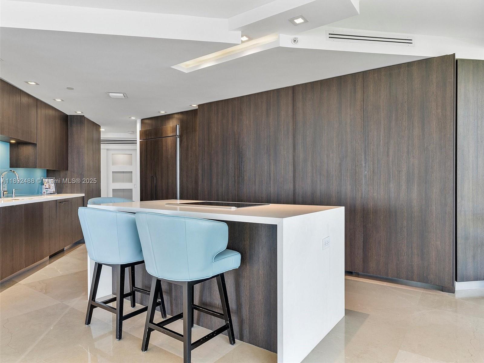 4000 Island Boulevard, Unit 606 Aventura, FL 33160 - Photo 13 of 36 a kitchen with a table chairs sink and cabinets