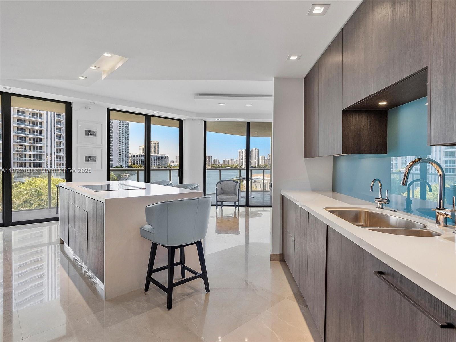 4000 Island Boulevard, Unit 606 Aventura, FL 33160 - Photo 16 of 36 a large kitchen with kitchen island a large counter space a sink a refrigerator and dining table