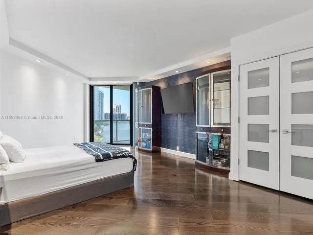 a spacious bedroom with a bed and wooden floor