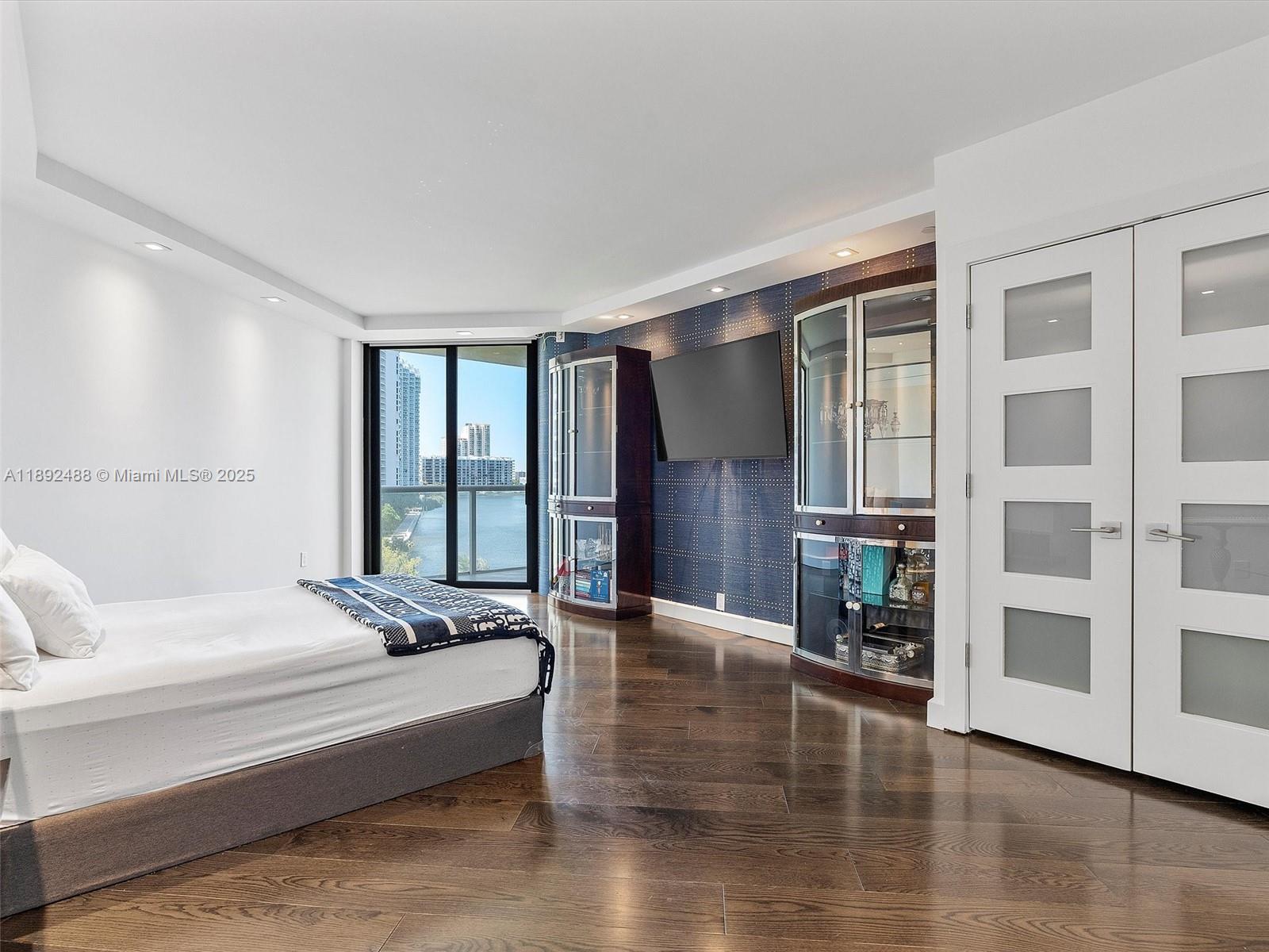 4000 Island Boulevard, Unit 606 Aventura, FL 33160 - Photo 30 of 36 a spacious bedroom with a bed and wooden floor