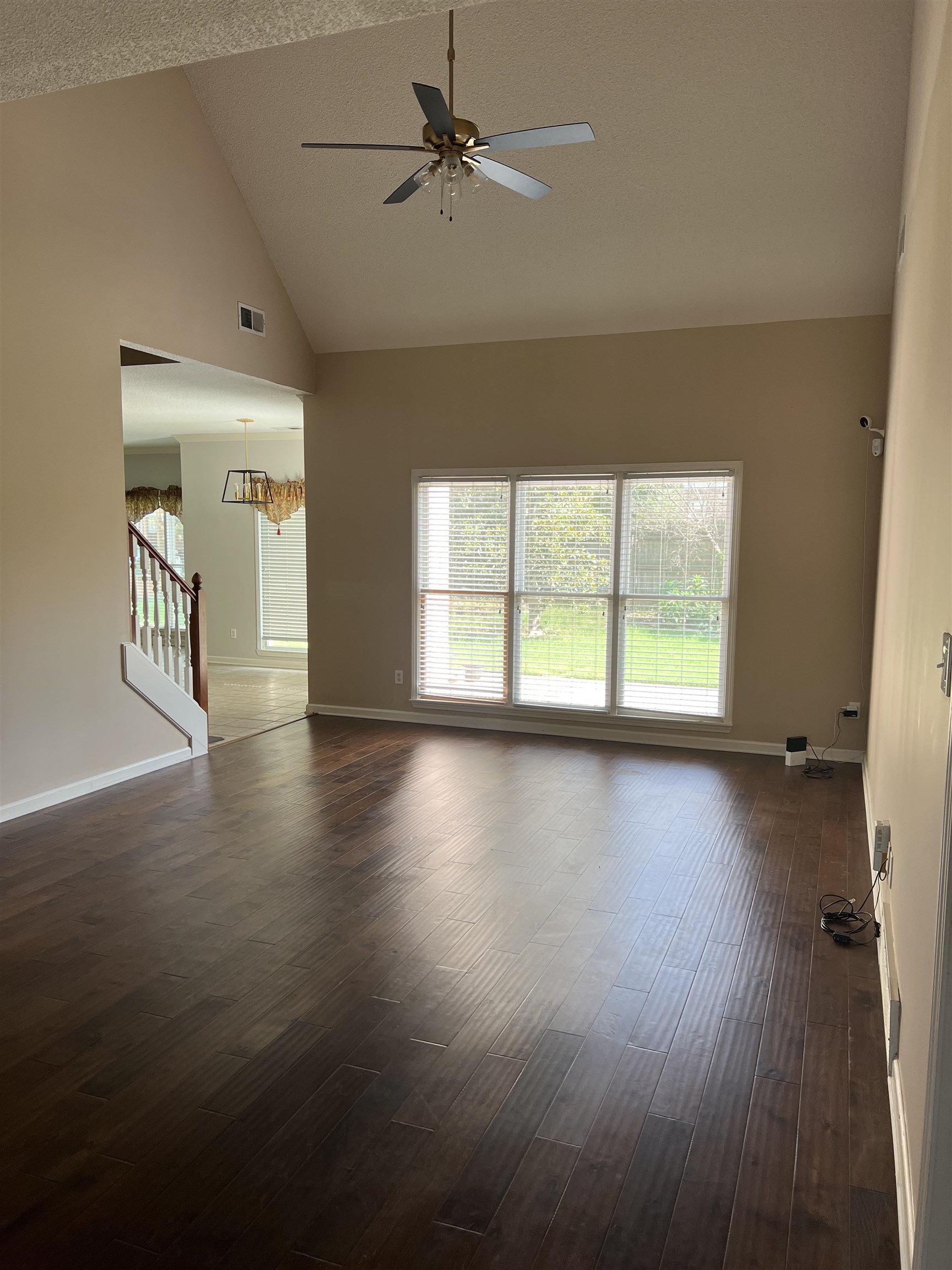 455 Hunters Mill Cove Collierville, TN 38017 - Photo 6 of 10 Unfurnished living room featuring dark wood-style floors, stairs, healthy amount of natural light, ceiling fan, and a textured ceiling
